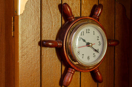 Wall clock in the shape of naval helm. Nautical style clock is attached to wooden box. Selective focus.の写真素材