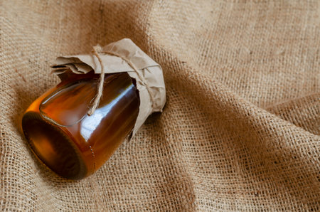 Healthy organic food concept. Natural honey in a glass jar on sackcloth. Raw liquid bee honey. Top view, close-up, selective focus.の写真素材
