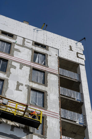 Thermal insulation of the walls of a new unfinished apartment building. Facade works on heat and moisture insulation of the outer walls of the building. Energy saving concept.の写真素材