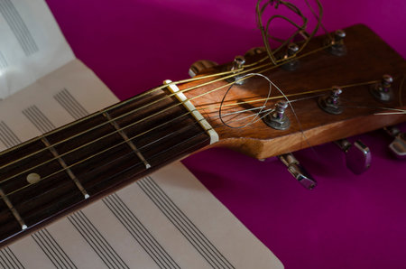 Close-up of an acoustic guitar fingerboard head and a blank sheet of music. Sunlight on a musical...