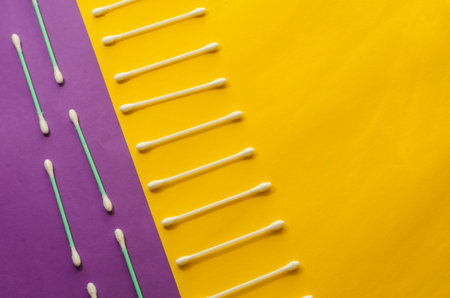 Minimalist background with cotton swabs on a lilac-yellow background. View from above at an angle....