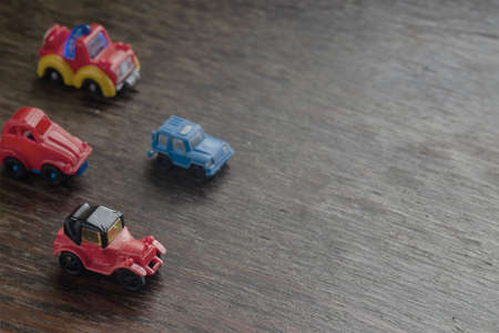 Children's imaginary concept games. Little Toy Cars racing headlong across a brown wooden surface. View from above at an angle. Selective focus.の写真素材