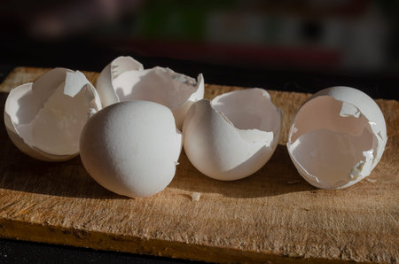White shells of chicken eggs close-up. Broken shell of five raw chicken eggs on a wooden cutting...