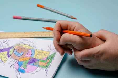 Mental health, a modern method of art therapy, Neurographics. The hands of an adult woman draw an abstract multicolored drawing on a white sheet of paper. Selective Focus.の写真素材