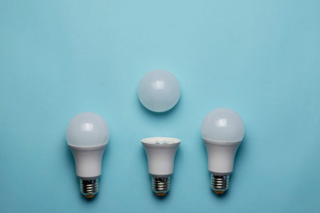 Creative minimalist composition with LED lights on a blue background. Two whole lamps and one with...