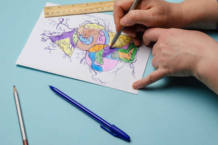 Mental health, a modern method of art therapy, Neurographics. The hands of an adult woman draw an abstract multicolored drawing on a white sheet of paper. Selective Focus.の写真素材
