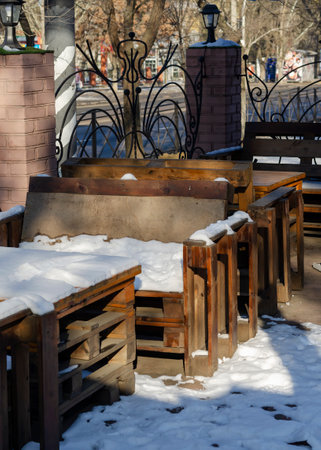 An empty street cafe covered with snow. Tables and chairs are made from pallets. Student cafe. No people.の写真素材