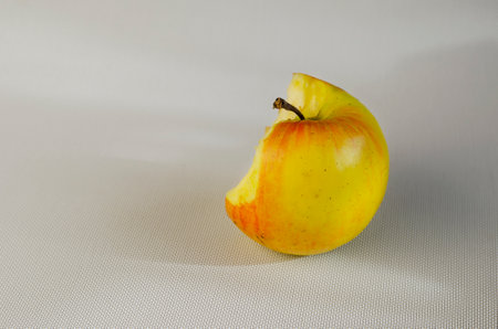 A half-eaten apple on a white background. A bitten ripe apple on a white background. Selective focus.の写真素材