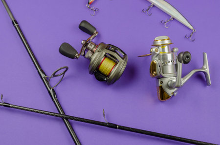 Fishing rod fly fishing reel, baitcasting reel and baits on blue background. Fishing, tackle, sport. Selective focus.の写真素材