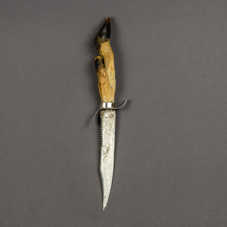 Goat foot knife on a gray background. An old knife with a saw and a handguard. Top view, flat lay.の写真素材