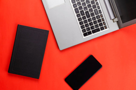Hardcover book, phone, laptop on a red background.Flat lay. No people.の写真素材