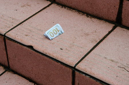 One hundred dollar bill lies on the red step outdoors. Folded Banknote on a wet street staircase....