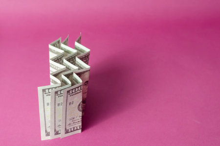 Accordion folded hundred dollar bills on a pink background. Abstract background with three banknotes.の写真素材