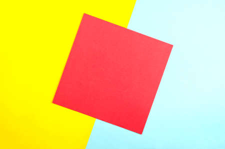 The red square on a pale yellow and blue background. Abstract geometric background of yellow, red and blue, created with overlapping paper. Top view, Flat Lay.の写真素材