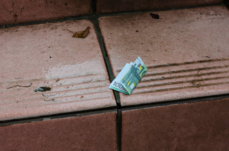 One hundred euro bill lies on the red step outside. Folded Banknote on a wet street staircase....