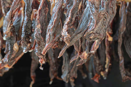 Hanging beef jerky close-up. Dried beef strips. Ready-to-eat treats. Dehydrated food. Selective focus.の写真素材