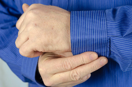 Midsection Of Man Buttoning Sleeve. A man buttoning his blue shirt. Blue shirt with thin stripes....