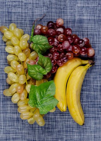 Ripe bananas and bunches of grapes on a white and blue background. Food, ingredients. Flat lay.