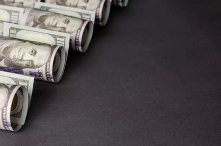 Creative abstract background with one hundred dollar bills on a gray background. A group of banknotes twisted into a cylinder. Close-up, selective focus.の写真素材