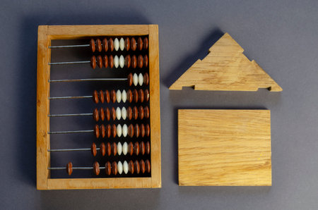 Old wooden abacus and a wooden house on a gray background. Top view, flat lay.