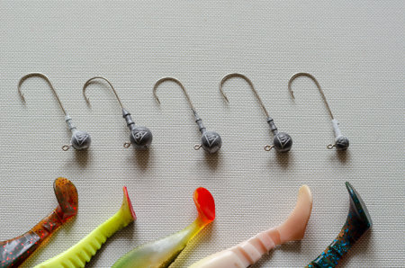 Random jig heads and fragments of rubber lures lie on a white textured background. A special device...