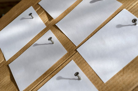 Six Note Paper Stickers are screwed to the brown cardboard with metal screws. White blank square...