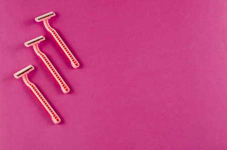 Pink plastic razors on a pink background. Three new women's razor. Selective focus. Copy spaceの写真素材