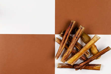 Helpful dried treats for pets. Dried bovine penis, bully sticks, beef pizzle for dogs on a brown and white background. A mix of random treats of different lengths and diameters.の写真素材