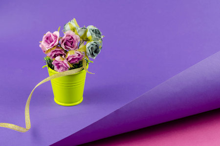 Yellow metal bucket with a bouquet on a two-color abstract geometric background. A bucket with...