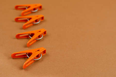 Brown plastic clothespins on a brown background. A line of new clothespins. Side view at an angle. Selective focus. Copy spaceの写真素材