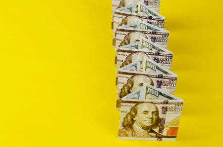 Geometric composition of money on a yellow background. Line lined with one hundred dollar bills in...