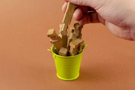 Small bucket, wooden puzzles and a hand on a brown background. A man's hand pulls out a child's...