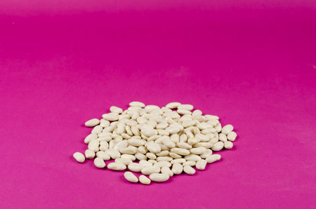 Dry white beans on a pink background. A pile of scattered legumes. Close-up, selective focusの写真素材