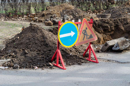 Repair and restoration work on a city street. Wooden fence with warning signs near the excavated trench. A water pipe bursting.の写真素材