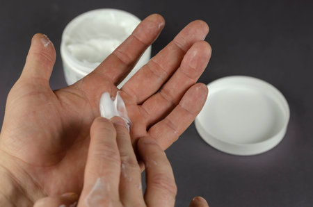 Hand rubs cosmetic cream into hand. A middle-aged man takes care of the skin of his hands. A...