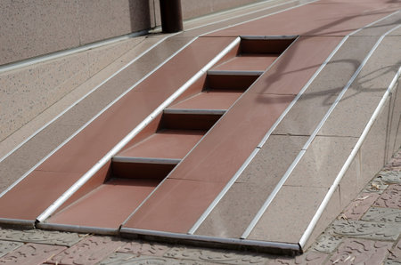 Brown and beige ramp for the disabled with steps. Entrance to the building for people with...