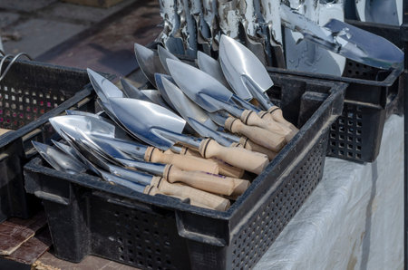 A counter with new metal garden tools. Garden scoops and shovels in black plastic boxes. Spring Farmer's Fair. Gardening and crop production.の写真素材