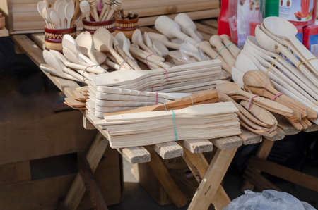 Local market counter with wooden kitchen products. Spoons, shovels, potato grinders, rolling pins, honey spoons and other goods. Large assortment of kitchen utensils. Spring Fair.の写真素材