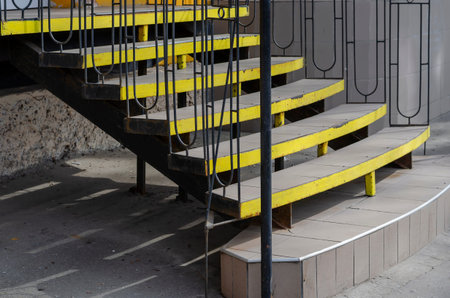 Black and yellow steps with a railing. Entrance to the building. Natural light, daytime. Selective...