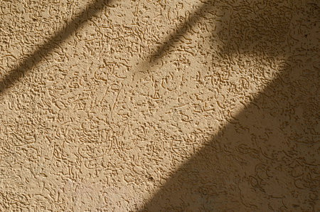 Yellow concrete wall with small dark depressions and stripes. Cement texture with shadows. Abstract background.の写真素材