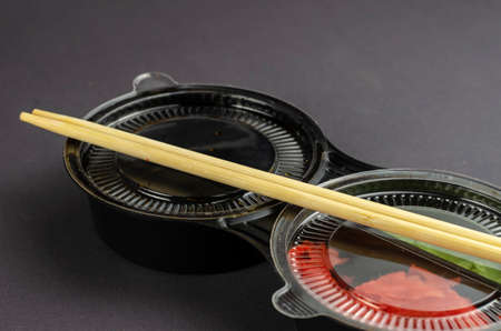 Disposable plastic container with sushi sauces and bamboo sticks on a gray background. Ginger Wasabi And Soy Sauce In Take Away Box. Takeaway food.の写真素材