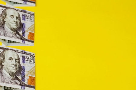 Geometric composition of money on a yellow background. Line lined with one hundred dollar bills in...