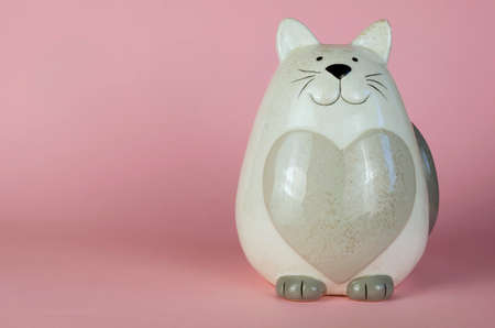 Cat piggy bank on a pink background. Gray ceramic cat-shaped penny bank. Side view. Copy spaceの写真素材