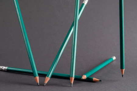Abstract geometric composition with standing pencils on a gray background. A group of green pencils stand randomly at different angles. Side view. Selective focus.の写真素材