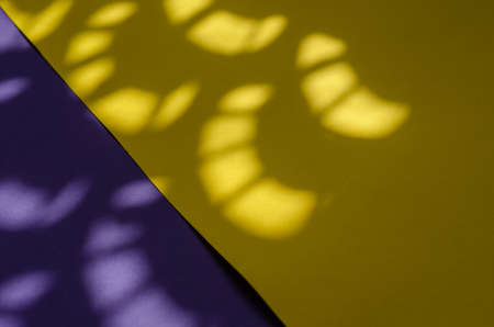 Minimalist light and shadow composition on a yellow and lilac background. Abstract sunspots on a two-color background.の写真素材