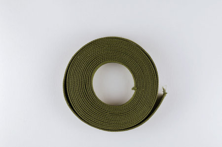 A roll of green cotton ribbon on a white background. Sturdy Tape for making, slings, straps, sewing...
