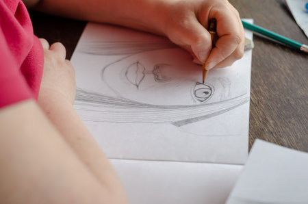 An adult woman draws a portrait with a pencil on paper. The process of creating a portrait, learning...