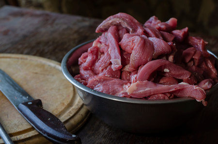 Cooking beef meat dishes. A portion of raw meat for beef stroganoff in a metal bowl. Cutting board,...