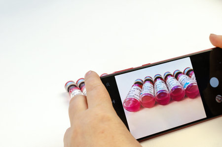 Woman taking pictures by smartphone Animal rabies vaccine Biocan R from Bioveta is on white....