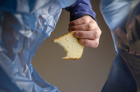 A hand tosses the bread into the trash can. A man holds a bite of bread over the garbage basket. View from below. Indoors.の写真素材